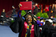 An IU South Bend graduate proudly holds up her degree.
